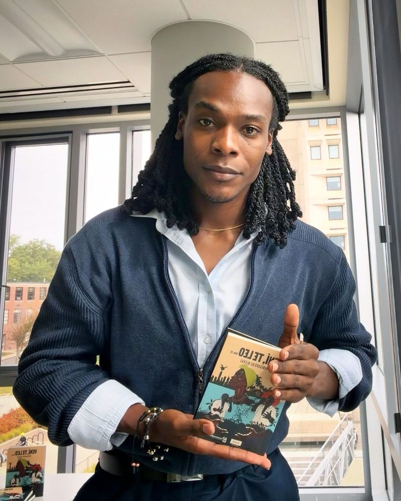 Deyner Caicedo Camacho holding a copy of the anthology Vení, te leo, volume 2
